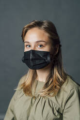 Junge Frau mit Gesichtsschutzmaske bei COVID-19 - MEUF04346