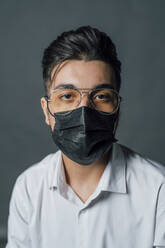 Young man wearing protective face mask in studio during COVID-19 - MEUF04389