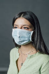 Young woman in protective face mask during pandemic - MEUF04395