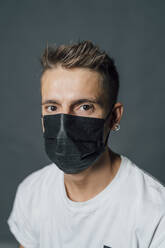 Junger Mann mit Gesichtsschutzmaske im Studio - MEUF04405