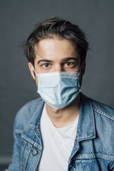 Junger Mann mit Gesichtsschutzmaske während COVID-19 - MEUF04411