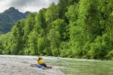 Reife männliche und weibliche Freunde sitzen am fließenden Fluss im Wald während der Ferien - ANSF00020