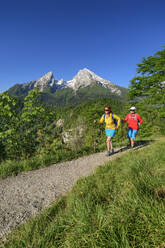 Männliche und weibliche Freunde beim Wandern in den Chiemgauer Alpen an einem sonnigen Tag - ANSF00031