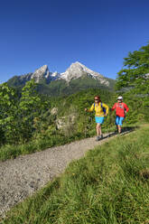 Male and female friends hiking at Chiemgauer Alps during sunny day - ANSF00031