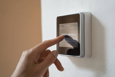 Woman touching smart home automation device on wall - DIGF16584