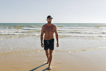 Hemdloser Mann mit Mütze am Strand - JRVF01965