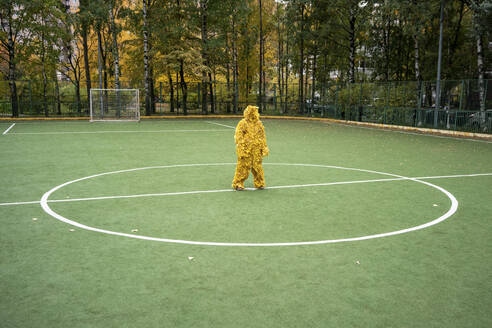 Frau mit gelbem Blattkostüm auf dem Sportplatz - VPIF05051