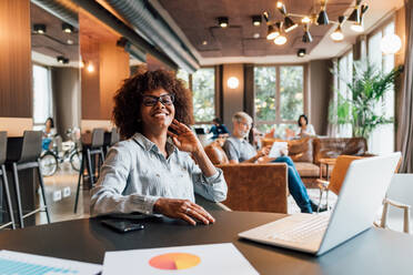 Italy, Portrait of smiling businesswoman at table in creative studio - ISF25163