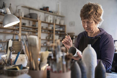 Spain, Baleares, Woman painting ceramics in workshop - ISF25282