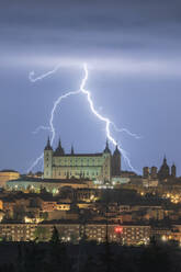 Stadtbild mit gealtertem berühmten Schloss Alcazar von Toledo in Spanien unter bewölktem Himmel in der Nacht während eines Gewitters platziert - ADSF31086