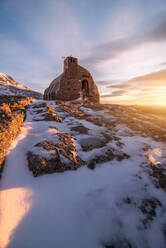 Malerische Landschaft kleinen alten Steinhaus auf verschneiten Gipfel der Berge unter bunten bewölkten Himmel bei Sonnenuntergang platziert - ADSF31131