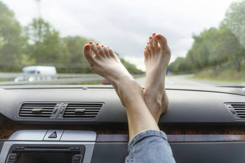 Mature woman with feet up on car dashboard - CHPF00788