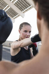Female athlete with male instructor practicing boxing - PNAF02380