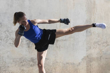 Sportlerin beim Kickboxen vor der Wand - PNAF02385