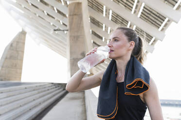 Müde Sportlerin, die Wasser aus einer Flasche trinkt - PNAF02402