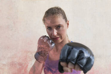 Female boxer showing punching gesture in front of wall - PNAF02411
