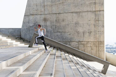 Sportswoman jogging on staircase - PNAF02415