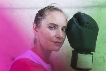 Sportswoman with boxing glove in front of wall - PNAF02432