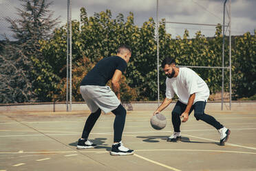 Männliche Freunde spielen Basketball auf dem Sportplatz - ACPF01332