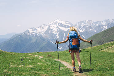 Female backpacker hiking on mountain during sunny day - OMIF00132