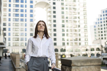 Thoughtful woman with hand in pocket standing at railing - LLUF00143