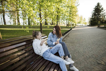 Mutter und Tochter unterhalten sich beim Essen im Park - LLUF00148