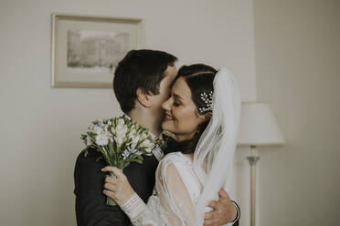 Bräutigam umarmt lächelnd die Braut zu Hause - SSGF00006
