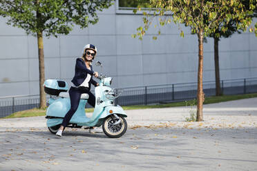 Lächelnde Geschäftsfrau auf einem Motorroller - AANF00110