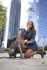 Woman crouching by pet dog on footpath - OCMF02271