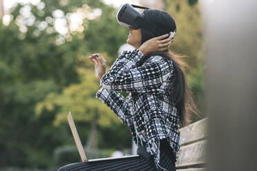 Geschäftsfrau mit Laptop und Virtual-Reality-Headset im Park - JCCMF04145