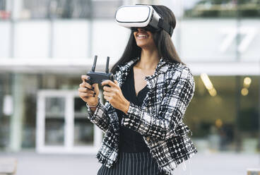 Glückliche weibliche Fachkraft mit Fernbedienung und Virtual-Reality-Headset - JCCMF04146