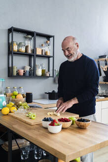 Man cutting fruits at kitchen counter - GIOF13781