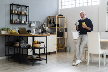 Man having coffee while using mobile phone at home - GIOF13854
