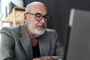 Älterer Geschäftsmann mit Brille und Laptop im Studio - GIOF13868