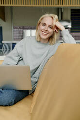 Geschäftsfrau mit Laptop auf dem Sofa in einem Coworking-Büro - OGF01108