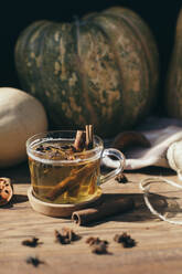 Pumpkins and glass of hot tea with cinnamon and star anise - MOMF00924