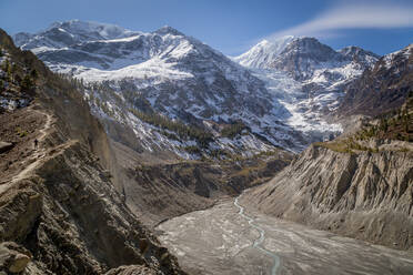 Malerische Landschaft mit einem kurvenreichen Fluss, der zwischen hohen steilen Bergen mit schneebedeckten Gipfeln im Hochland von Nepal fließt - ADSF31181