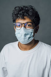 Man with protective face mask against gray background - MEUF04426
