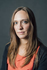 Serious woman with brown hair against gray background - MEUF04429