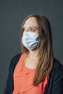 Young woman in protective face mask against gray background - MEUF04432