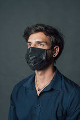 Mann mit schwarzer Gesichtsschutzmaske vor grauem Hintergrund - MEUF04455