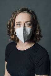 Woman wearing protective face mask against gray background - MEUF04515