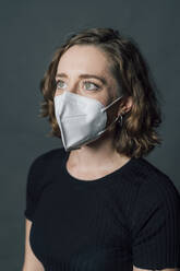 Woman in protective face mask against gray background - MEUF04516