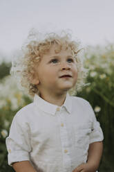 Lächelnder kleiner Junge mit blondem Haar auf einem Blumenfeld - SSGF00025