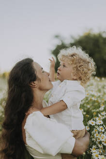 Mutter trägt ihren Sohn auf einem Blumenfeld - SSGF00027
