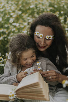 Lächelnde Mutter schenkt ihrer Tochter auf dem Feld eine Blume - SSGF00039