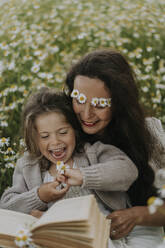 Glückliche Mutter und Tochter sitzen auf einem Blumenfeld - SSGF00040