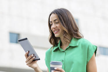 Lächelnde Frau mit Einwegbecher und digitalem Tablet - EIF02180