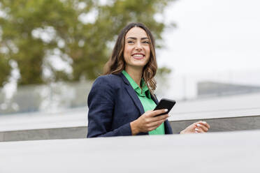 Smiling businesswoman holding smart phone - EIF02182