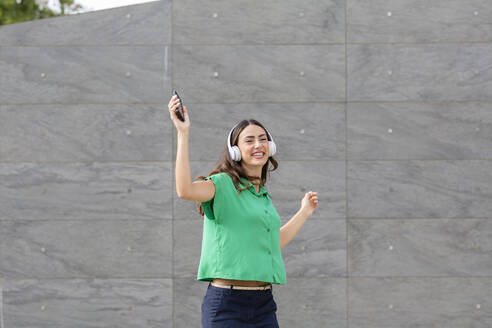 Glückliche Frau tanzt vor einer grauen Wand - EIF02187